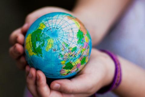 A small globe in the hands of a girl